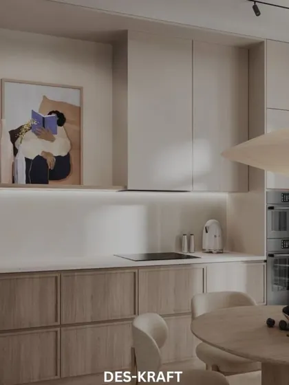 A view into a kitchen that blends seamlessly with the living area, featuring two-tone cabinetry and a piece of abstract art for a pop of color.