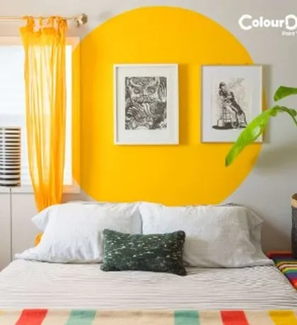 A bright and cheerful bedroom featuring a painted yellow circle as a modern headboard. This simple yet creative paint application adds a pop of color and a unique focal point to the room.