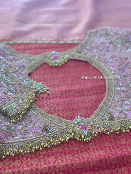 A lavender blouse with a heart-shaped back cutout, framed with heavy embroidery and tassels.
