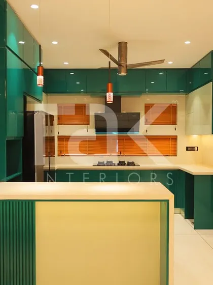 A bold and vibrant kitchen in the Palakkakkad home, using a striking teal color for the cabinetry, complemented by a breakfast bar and modern appliances.