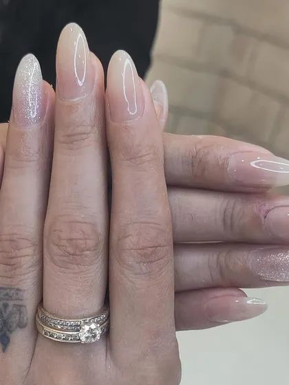 A delicate and ethereal look on long almond nails, with a sheer nude base and a subtle dusting of iridescent glitter on the accent nails.