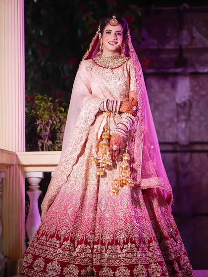 A full-length shot of the bride, showing the beautiful gradient of her pink lehenga. She looks so happy.