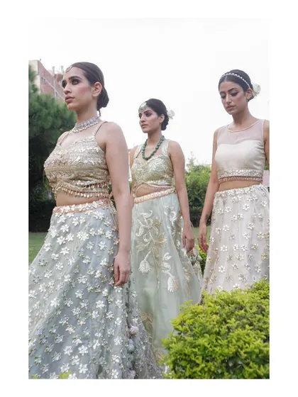 A candid-style group shot of three models in a garden, wearing complementary ethnic outfits. This image creates a narrative and shows how the pieces work together as a collection.