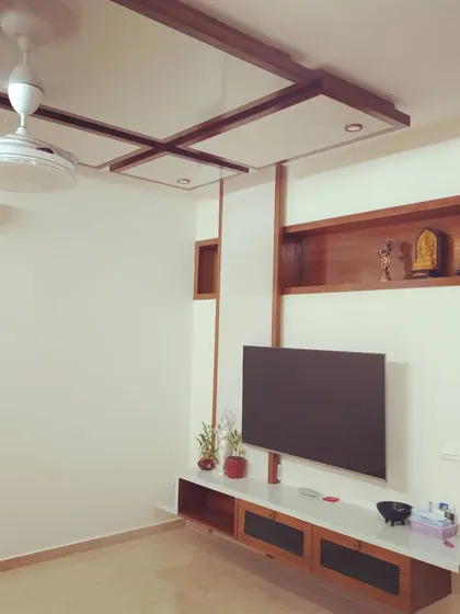 This television unit is an example of my "less is more" philosophy. The floating console keeps the floor clear, making the room feel larger, while the wood-paneled shelving and ceiling detail add architectural interest without clutter.
