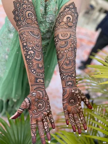 A breathtaking full-sleeve mehandi design, rich with detail. It combines peacock motifs, floral bands, and intricate fillers to create a truly royal bridal look.