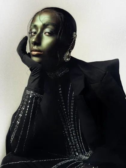 A full-look conceptual portrait showcasing the metallic makeup, sleek styling, and a powerful, composed pose.