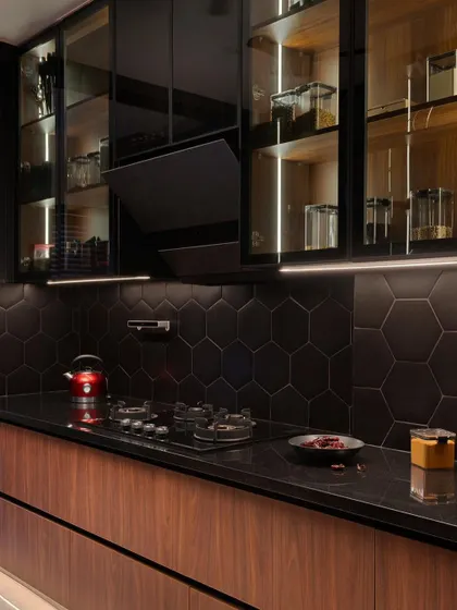 The finished kitchen, where the combination of black tiles, dark reflective surfaces, and warm wood creates a bold and modern culinary space.