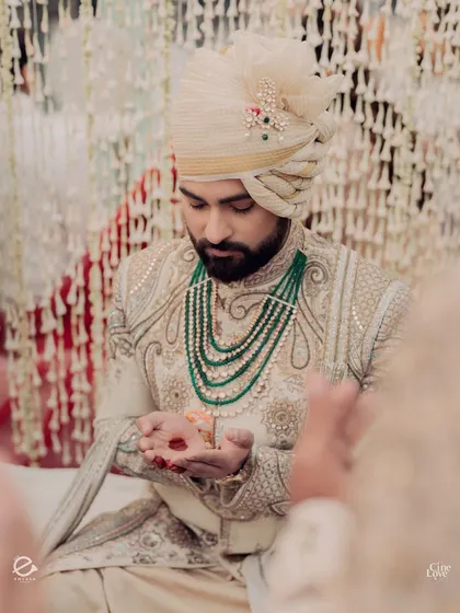 The groom, Bismil, during the Nikah rituals. His attire, with its intricate embroidery and emerald green necklace, perfectly complements the pastel green and white decor palette.
