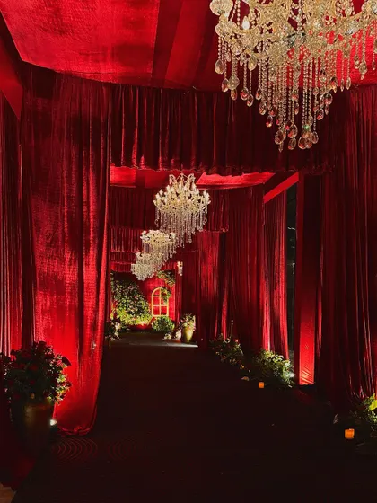 We designed this grand entryway to build anticipation. Guests walk through a tunnel of rich red velvet, guided by a series of cascading crystal chandeliers, leading them to the main event space.