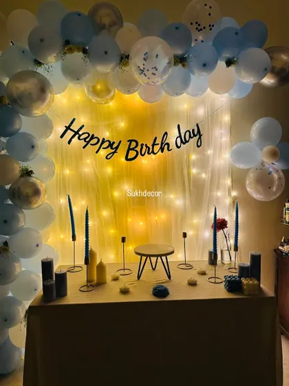 A simple yet elegant birthday setup. We created a backdrop of fairy lights and a balloon half-arch, with a beautifully arranged cake table featuring candles and a small stool.