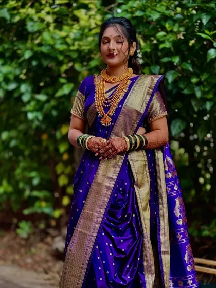 A classic bridal Nauvari in a rich purple Paithani silk. The drape is kept clean and traditional to let the beauty of the saree and the bride shine through.