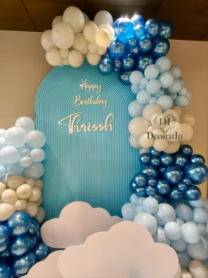 The beautiful blue and white balloon arch frames the custom-rippled backdrop for this dreamy first birthday.