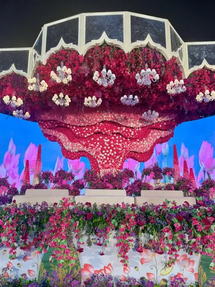 The alchemy of hues is truly unreal. This stage, with its massive floral ceiling installation and LED backdrop, is a sight for sore eyes and a testament to bold design. 🩷💜