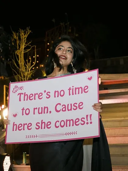 "There's no time to run, cause here she comes!" A playful sign held by a bridesmaid, building up the excitement for the bride's grand entrance.