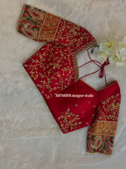 A vibrant red blouse with sleeves featuring a patchwork of brocade and intricate embroidery.