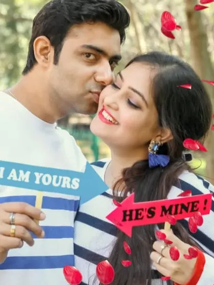 A playful and cute pre-wedding photo using "I am yours" and "He's mine" props, with falling petals adding to the romantic fun.