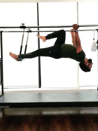 A client performs a hanging pike on the Cadillac. This is an intense core exercise that also builds upper body strength, perfect for rehabilitation and building resilience.