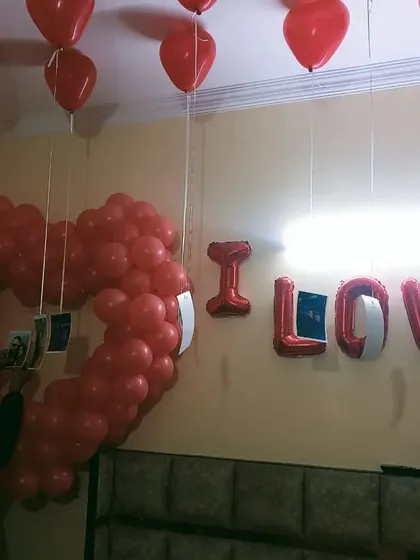 A romantic room setup with a heart-shaped balloon frame and "I LOVE U" letters.