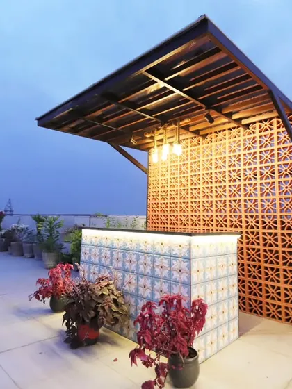 The custom-built bar at our Palam Vihar, Gurgaon project. The bar features a tiled front and is set against a terracotta jaali screen.