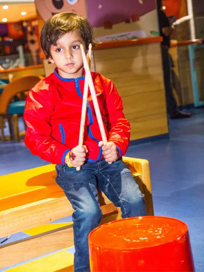 A young boy pretends to be a drummer, finding creative ways to play in our versatile space.