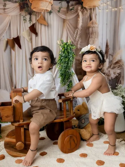 A moment of teamwork and play as one sibling pushes the other on a wooden tricycle.
