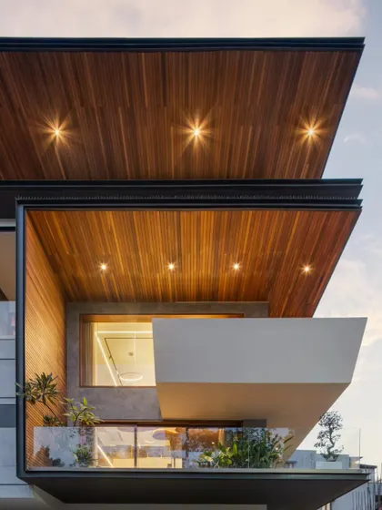 A detail of the Timber Edge facade at dusk, highlighting the warm tones of the timber-clad ceiling and the clean lines of the cantilevered structure. This view emphasizes our focus on material quality and atmospheric lighting.