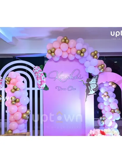 A close-up of the pink and gold balloon details on the butterfly party backdrop.