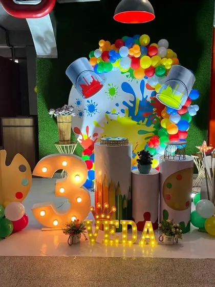 A vibrant and creative art-themed party, with props like paint buckets spilling colorful balloons, a paint palette, and brushes.