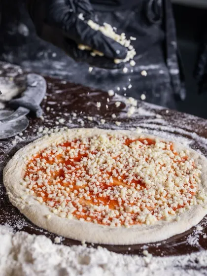 A generous amount of cheese being sprinkled onto a pizza base. For me, there's no such thing as too much cheese when it comes to making the perfect pie.