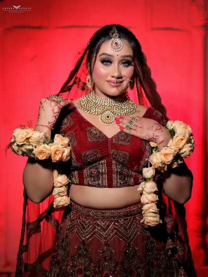 A happy bride posing with floral garlands. This shot captures the joy of the occasion, with the vibrant red of her lehenga and the soft colors of the flowers creating a beautiful contrast.
