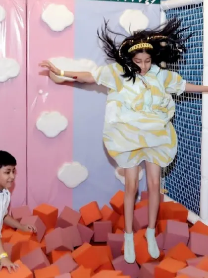 A girl joyfully jumps from the trampoline into a soft foam pit, one of our most popular and exciting activities.
