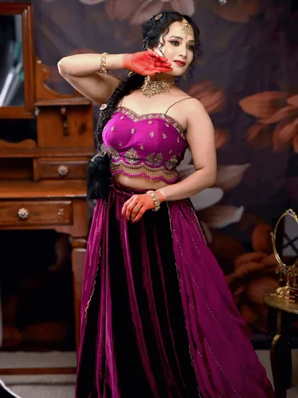 The rich velvet and magenta outfit is complemented by a makeup look that is both bold and elegant.