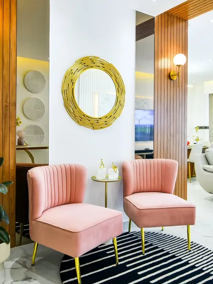 This entrance nook draws you in with its soft blush chairs, warm wood paneling, and a statement gold mirror. The combination of textures and colors creates a space that feels open, airy, and quietly elegant.