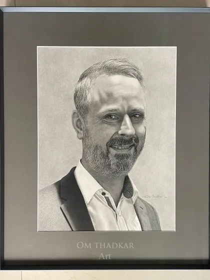 This is another example of a commissioned portrait, professionally framed. My process involves working closely with clients to understand the person I am drawing, which helps me to bring out their warm and approachable nature in the final piece.