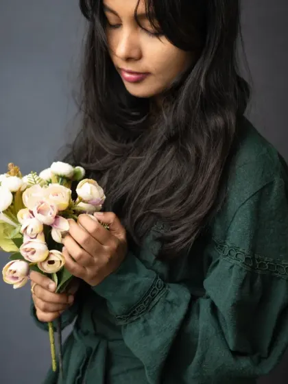 A soft and contemplative moment captured during a portrait session. The way she holds the flowers adds a touch of gentleness and introspection to this classic studio portrait.