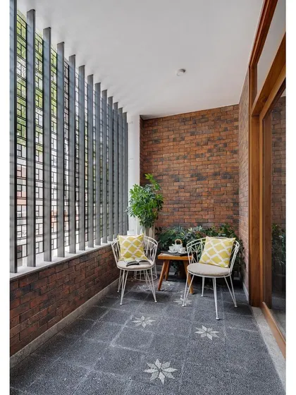 A private balcony in the Nataraj House, where a metal screen provides privacy and an exposed brick wall adds rustic texture.