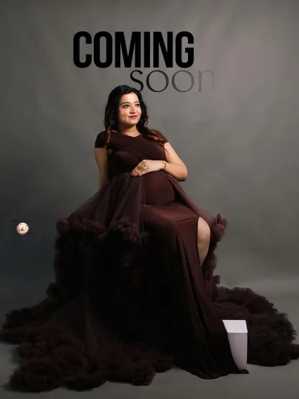 A hopeful and forward-looking portrait of the mother-to-be. Seated in an elegant brown gown, she gazes into the distance, with the words 'Coming Soon' hinting at the new arrival.