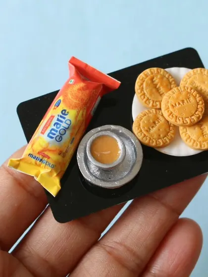 A close-up of a Marie Gold biscuit platter with a tiny cup of chai, a classic combination.