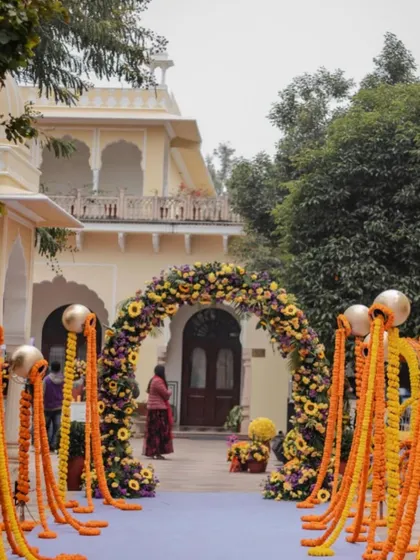 The entrance to a palace wedding's Haldi ceremony, featuring a grand arch of sunflowers and marigolds, blending tradition with a regal setting.