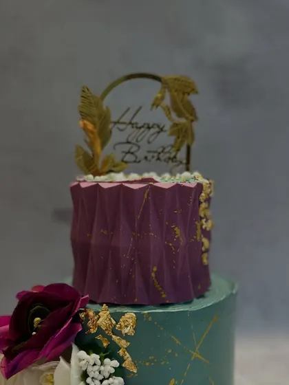 A close-up of the textured purple top tier and the custom gold "Happy Birthday" topper.