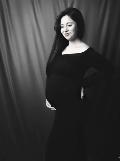A candid, gentle smile. This black and white image captures a natural and happy moment, showing the quiet joy of pregnancy.