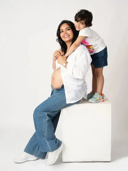 A happy and relaxed family portrait. The big sister gives her mom a hug from behind, and everyone is all smiles.