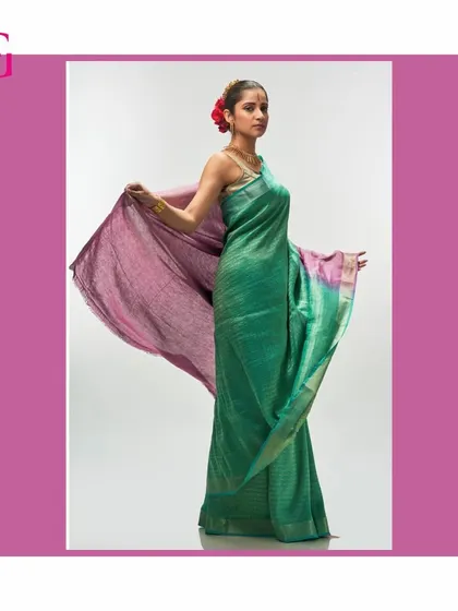 The green and purple silk linen saree is captured in motion, showing the beautiful flow of the fabric and the striking color combination.