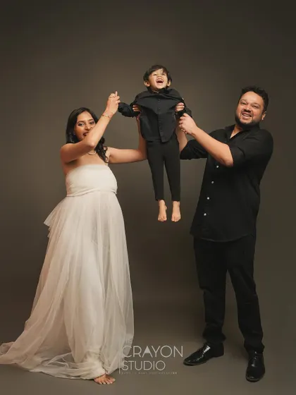 A moment of pure family fun. Lifting their son in the air brings out genuine laughter and joy, showing the lively energy of this growing family.