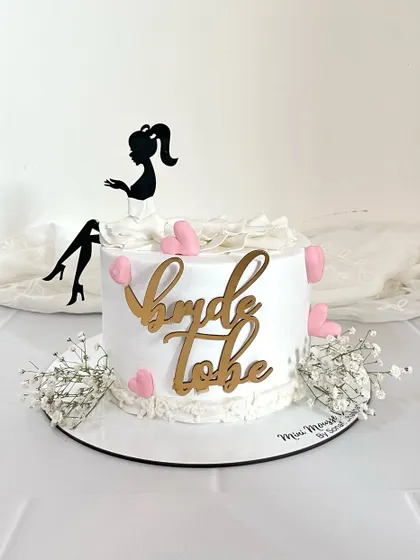Perfect for a bachelorette party, this 'Bride to be' cake is fun and chic. It features a silhouette topper, a textured gown effect, and is decorated with little pink hearts and fresh baby's breath.