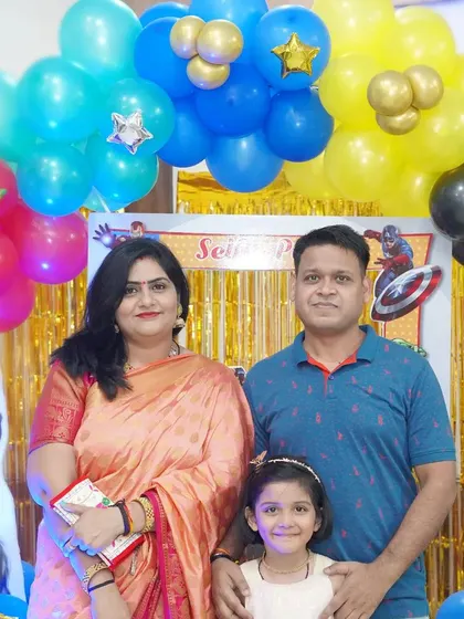 A family portrait in front of a vibrant, superhero-themed birthday decoration setup.