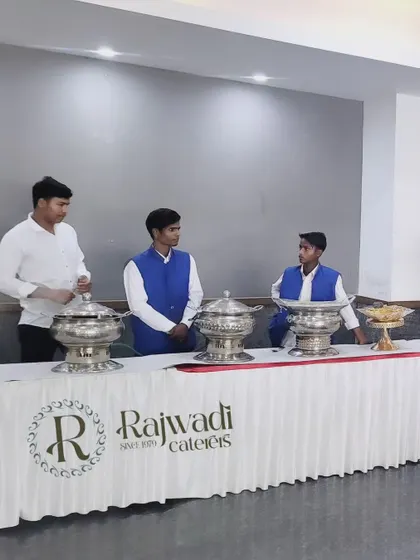 My staff standing behind a branded buffet table with classic silver chafing dishes. This showcases a more standard, yet highly professional, setup suitable for office meetings and seminars.