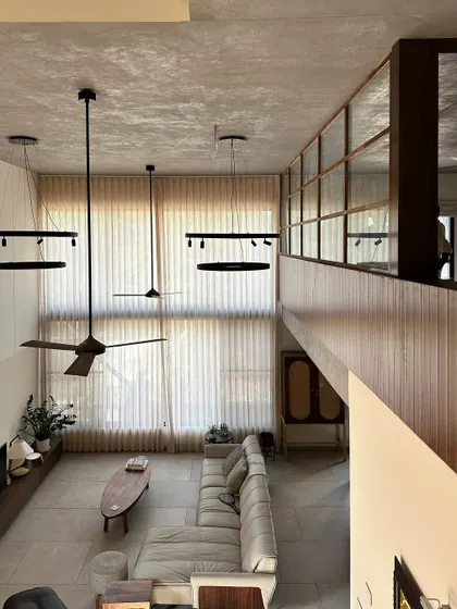 The Jayanagar Residence features a dramatic double-height living room. This high-angle view shows the scale of the space and the interplay of light from the large windows.