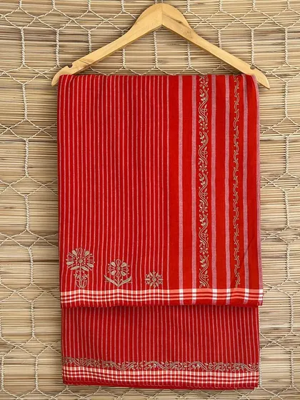 A bright red handloom saree with delicate Chikankari embroidery. The combination of traditional weaving and embroidery creates a stunning piece that celebrates Indian craftsmanship.