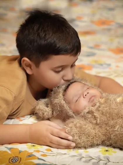 A tender kiss for the baby brother. This photo beautifully captures the love and affection between siblings.